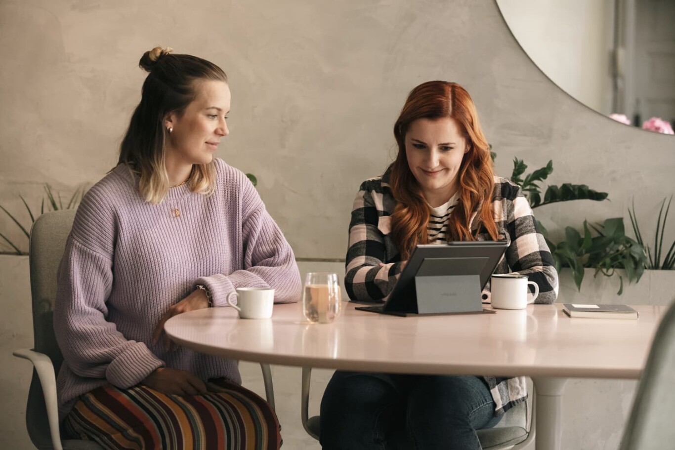 Two women having a conversation at a round table in a cafe.